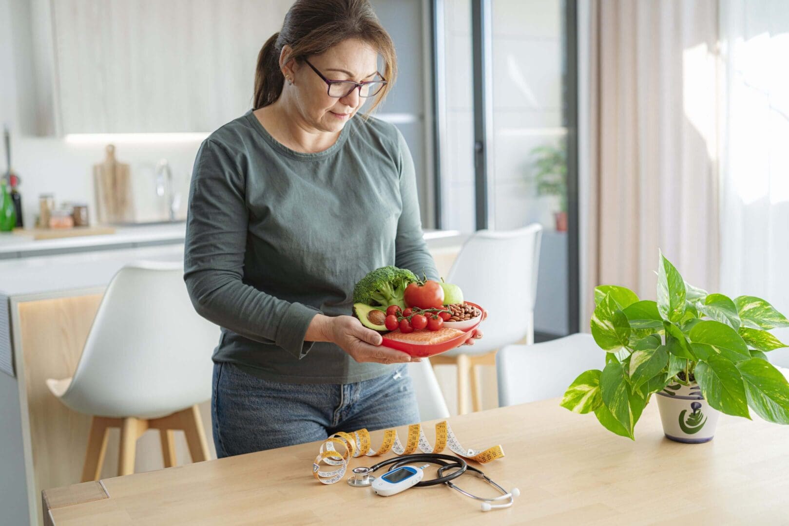 Woman preparing a fresh salad in a bright kitchen.