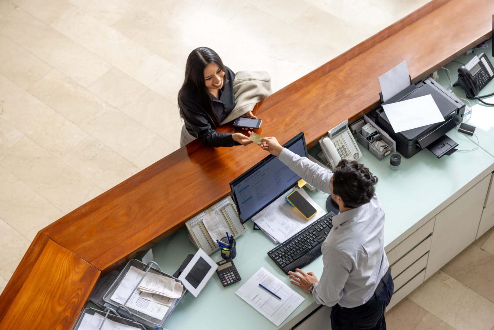 Two colleagues shaking hands across a desk in an office.