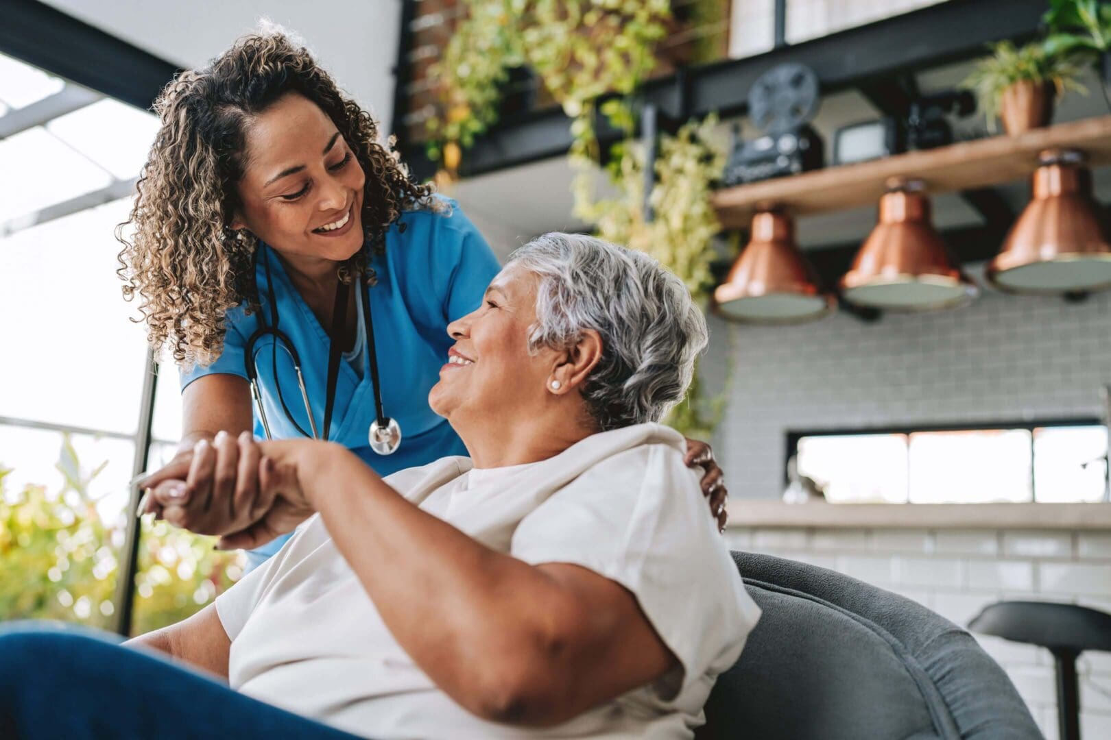 A nurse warmly holding hands with an elderly woman, sharing a joyful moment.