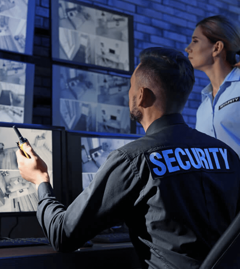 Security personnel monitoring multiple surveillance screens in a control room.