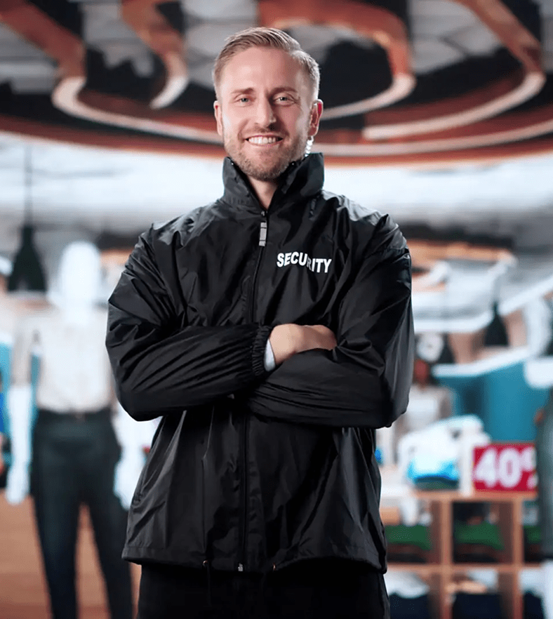 Smiling man in a black jacket stands confidently indoors.