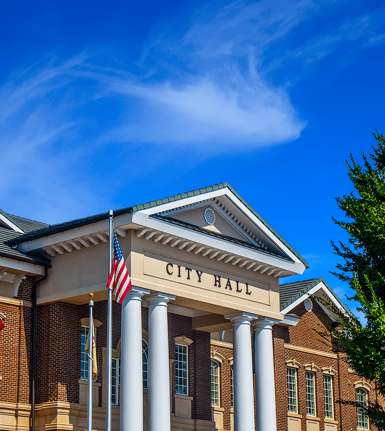 City hall building with an American flag under a blue sky.